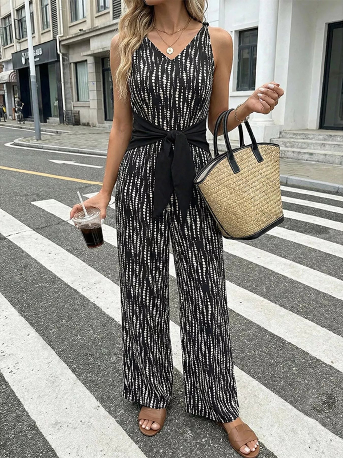 Black printed wide-leg jumpsuit with V-neck and waist tie, sleeveless