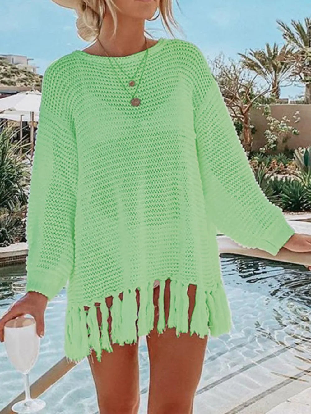 Neon green long-sleeve openwork knit cover up with tassel fringe hem.