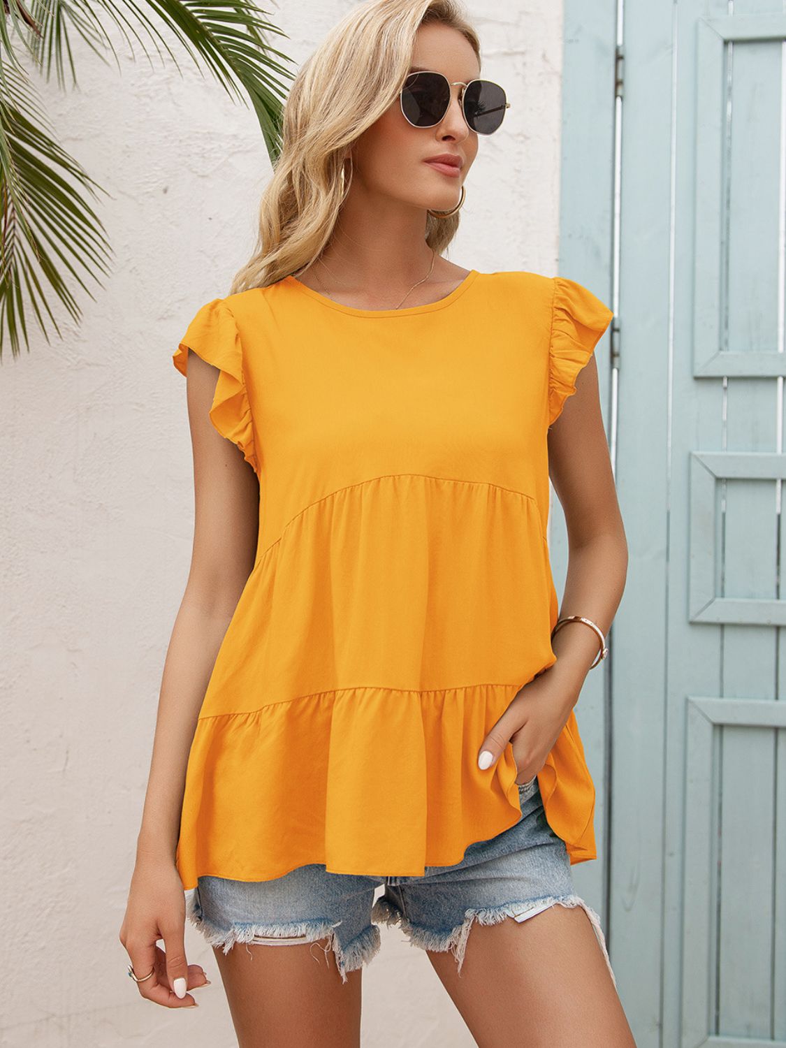Orange tiered blouse with round neck and flutter sleeves, layered ruffle hem