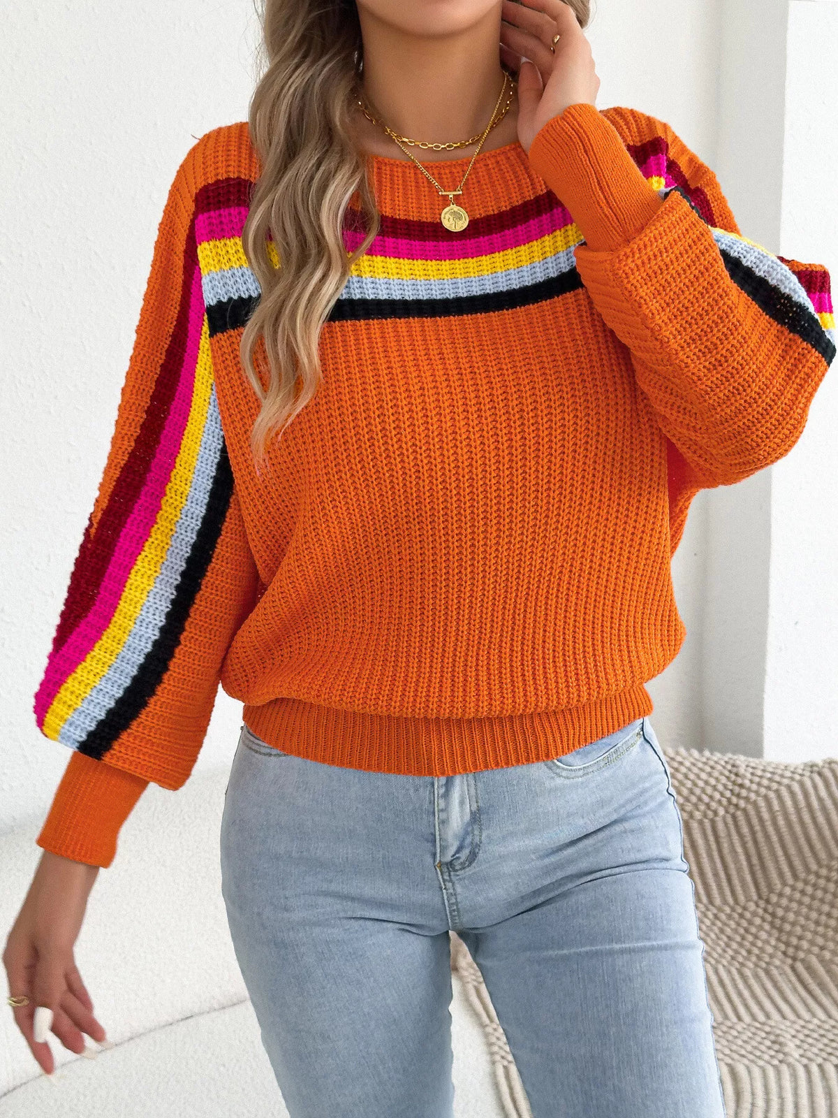 Orange ribbed knit boat-neck sweater with multicolor striped shoulder and sleeve bands.