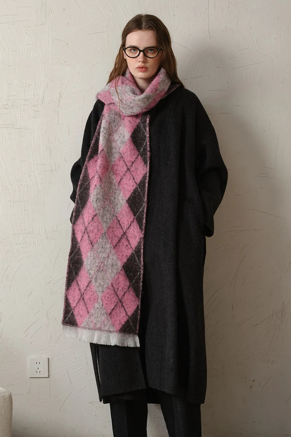 Pink argyle polyester scarf with fringed ends, pink and dark gray diamond pattern.