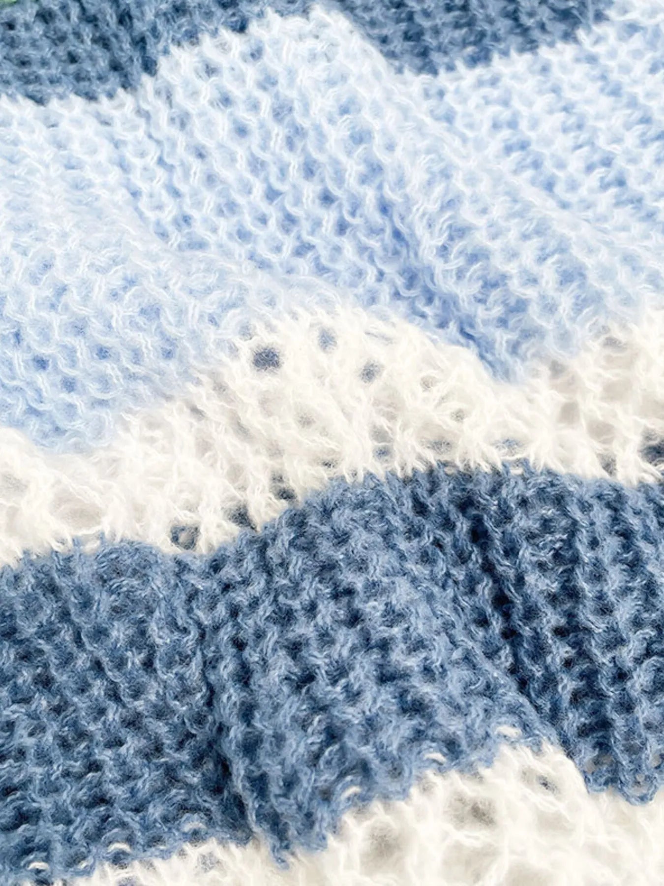 Striped openwork knit sweater close-up with horizontal color-block bands