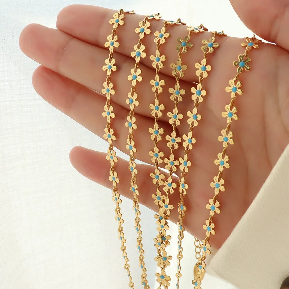 Gold-tone drip necklace with tiny blue flower clover links, multiple lengths shown in hand