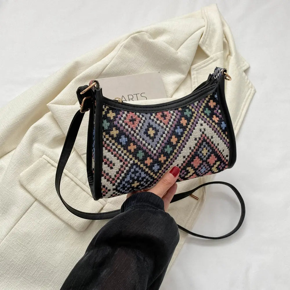 Cream crossbody bag with multicolor geometric print and black trim, top zipper