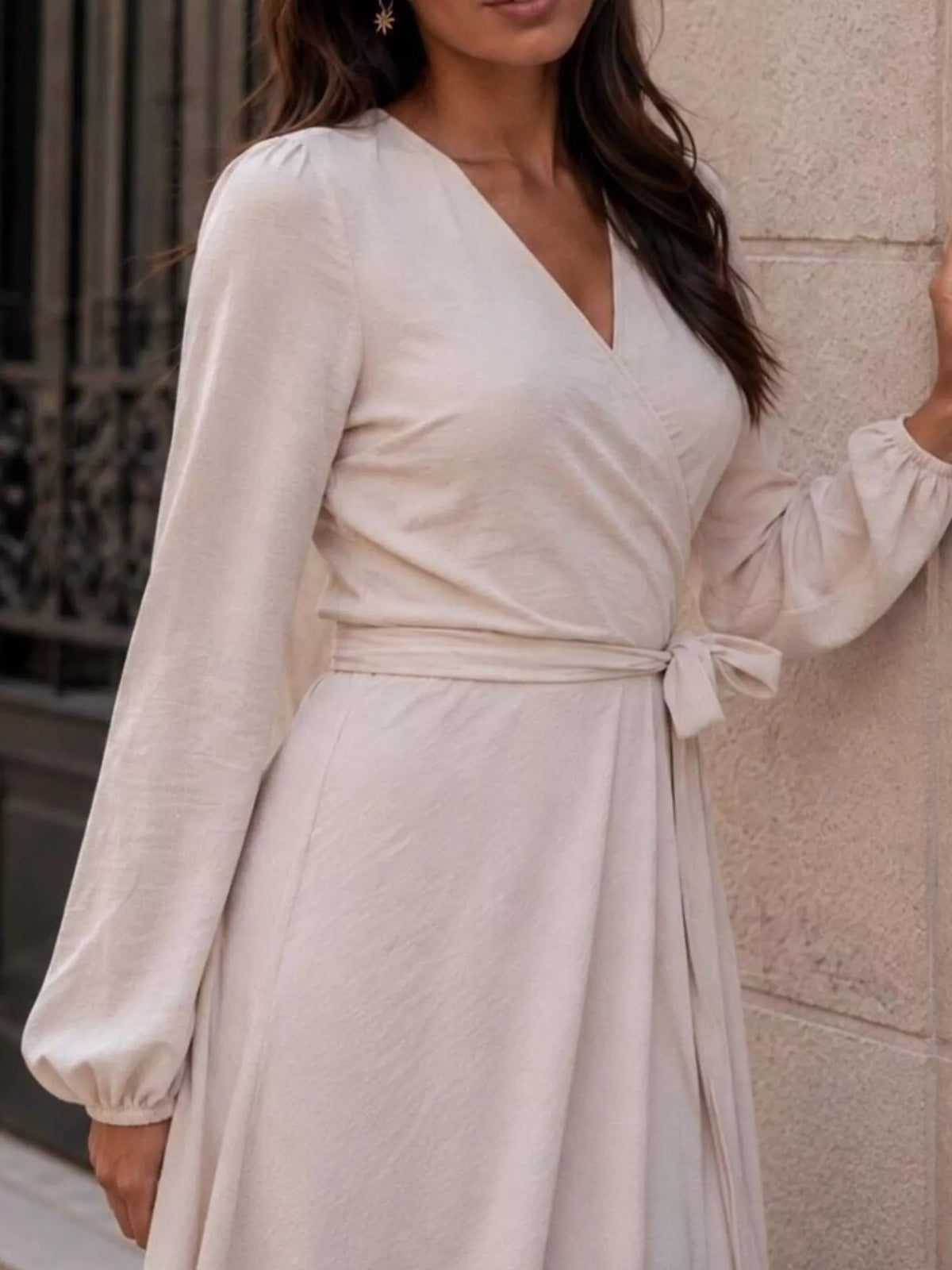 Beige long sleeve wrap dress with V-neck, draped front, and tied waist