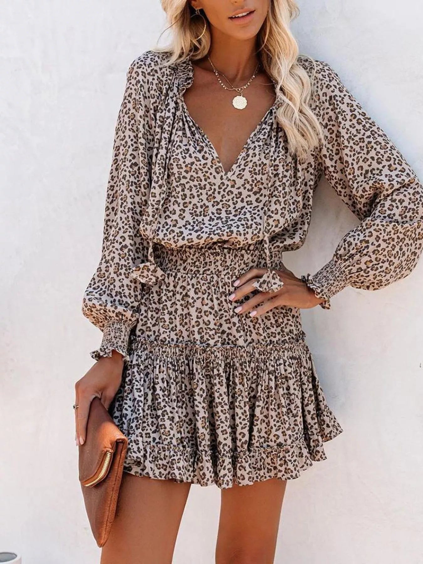 Tie-neck lantern sleeve dress in camel leopard print with elastic waist and ruffled hem.