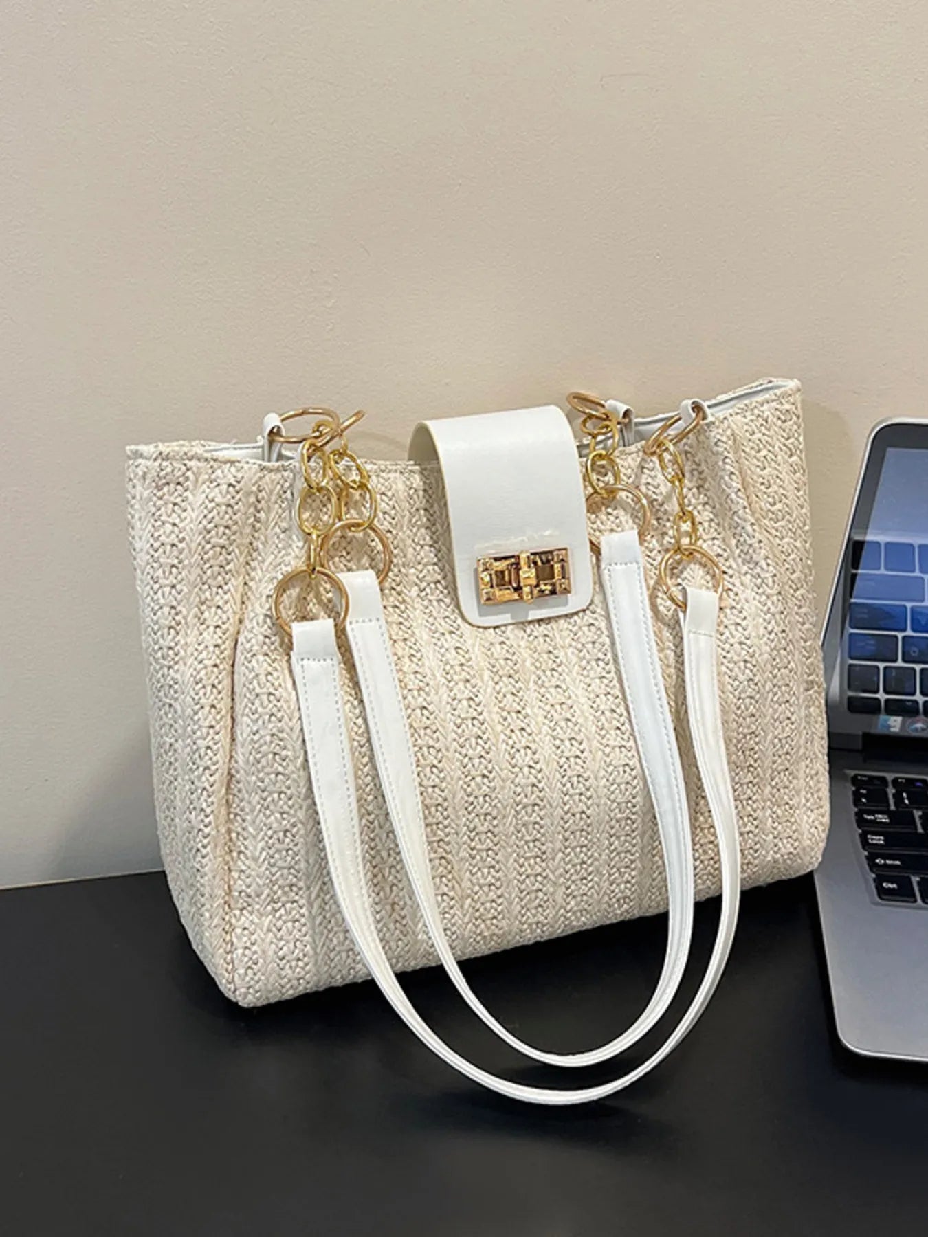 Beige woven straw shoulder bag with white straps, gold chain details, and square clasp