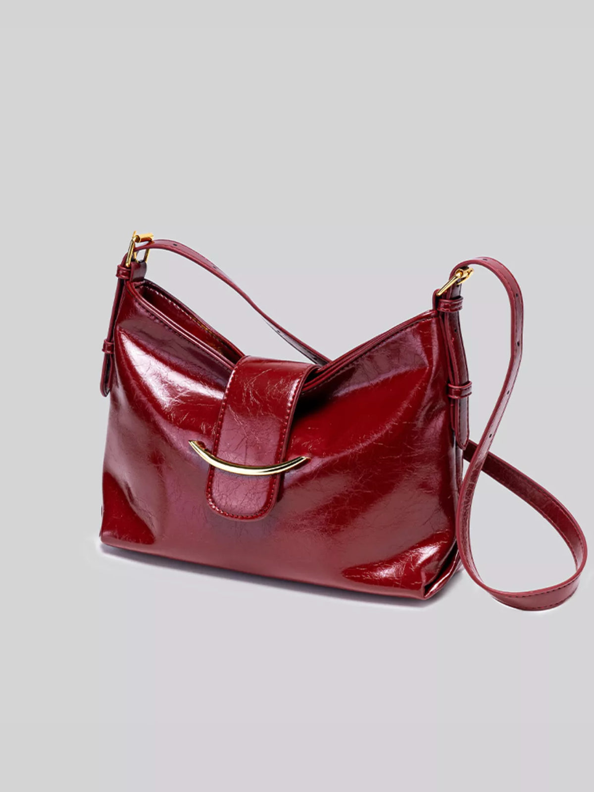 Wine red gloss vegan leather crescent shoulder bag with crossbody strap and gold-tone hardware