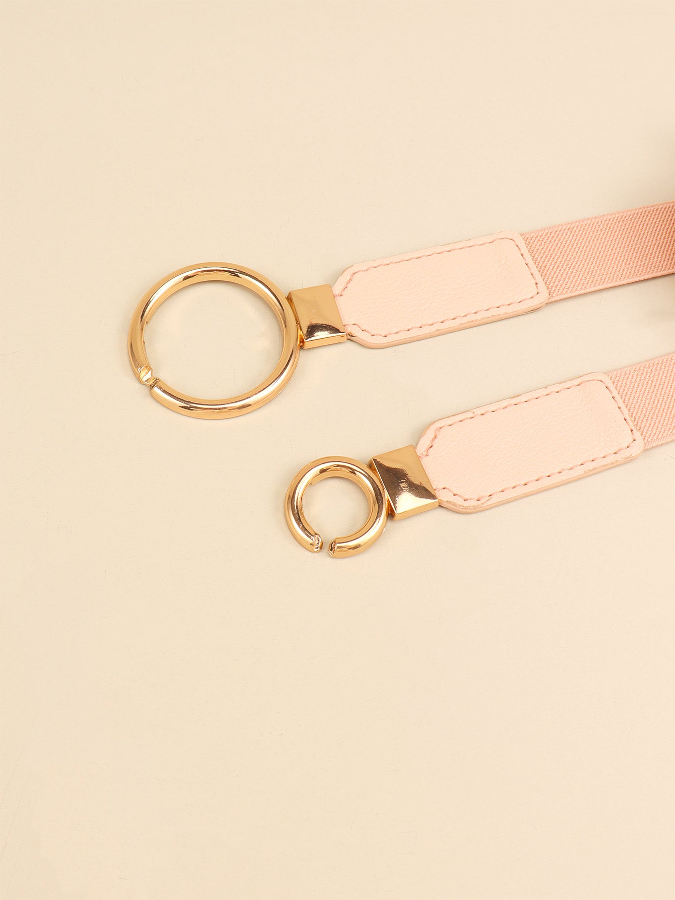 Light pink belt close-up with double ring buckle and stitched strap panels
