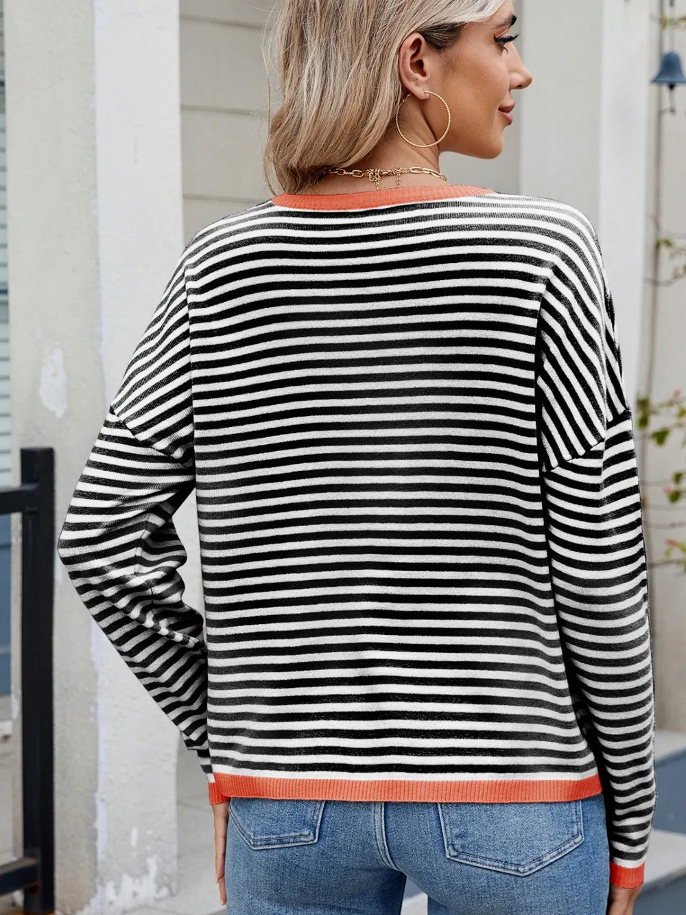 Striped contrast crewneck sweater, black and white stripes with orange rib trim, back view