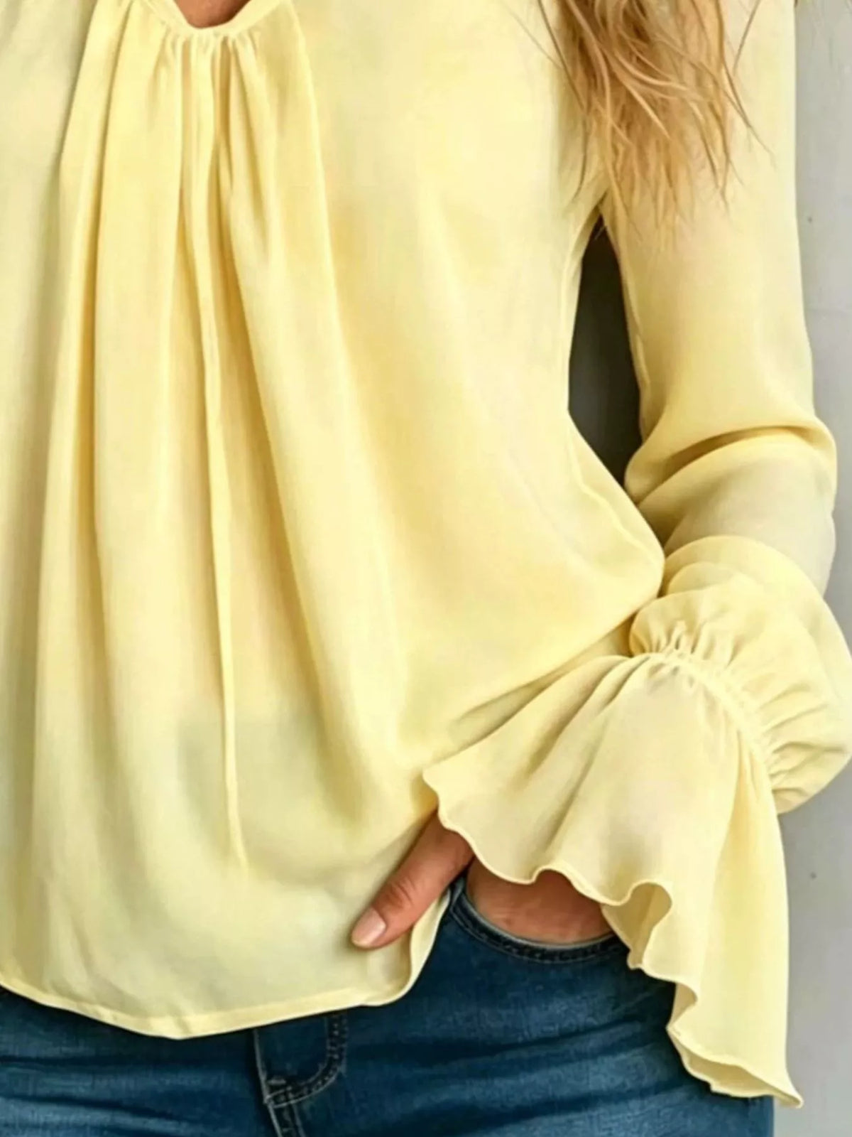 Pastel yellow v-neck polyester blouse with pleated front and ruffled flounce sleeve cuffs