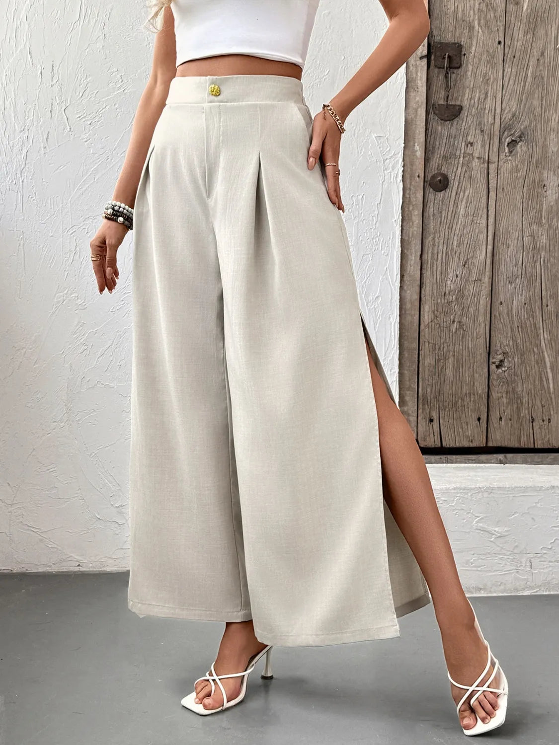 Beige wide-leg pleated pants with side slits and high waist button detail