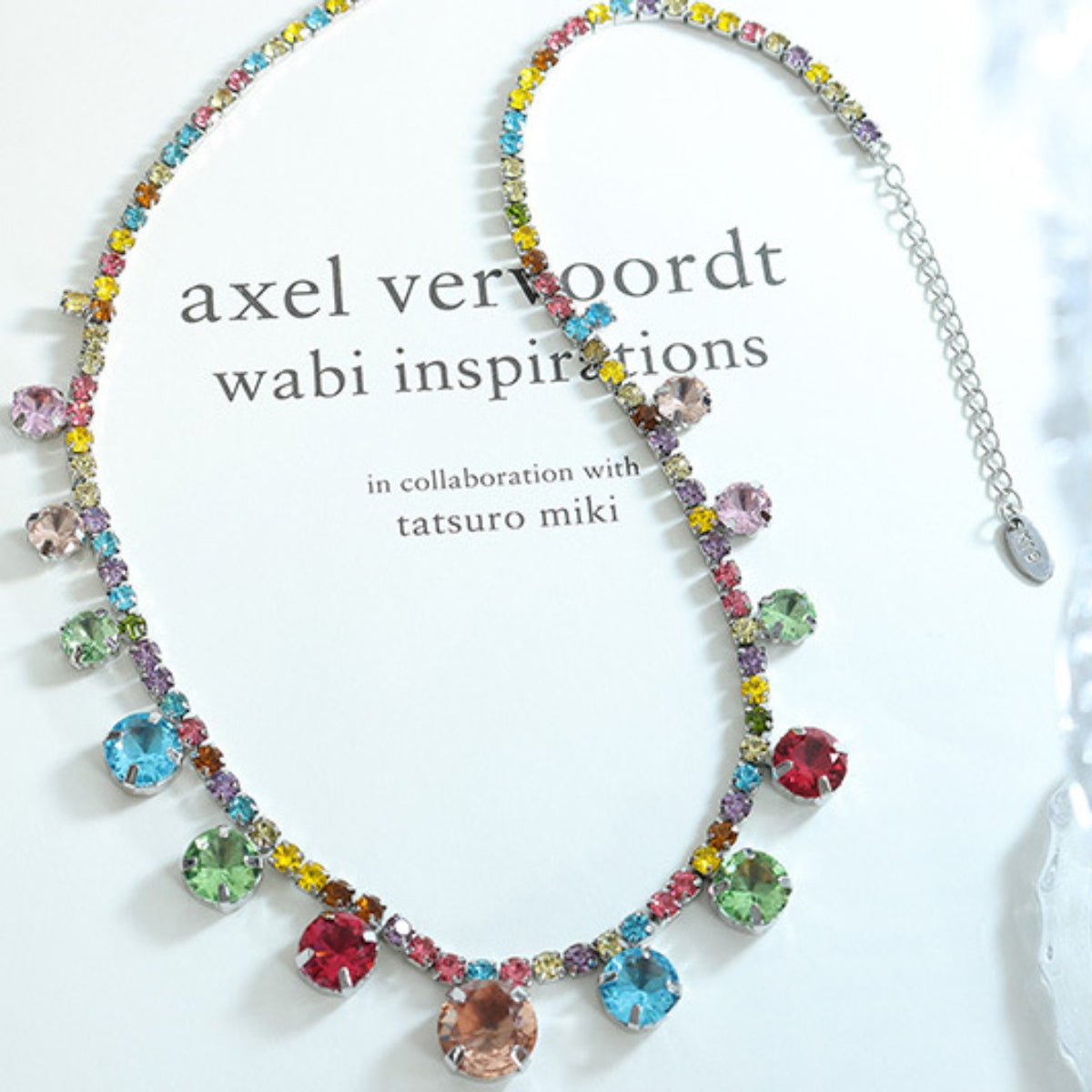 Crystal charm necklace with multicolor stones on silver-tone chain, flat lay