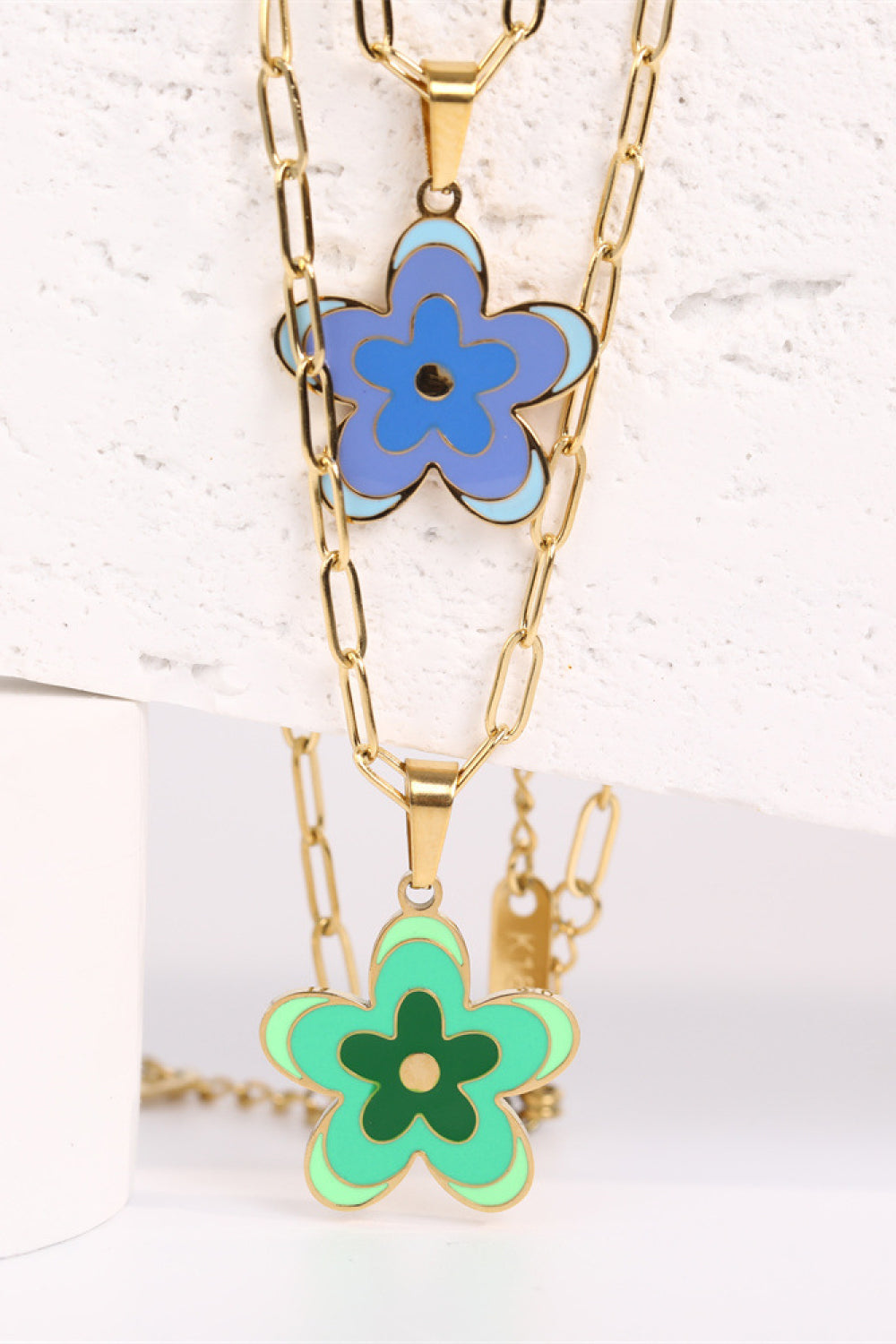 Gold-tone flower pendant necklace with blue enamel flower and green charm