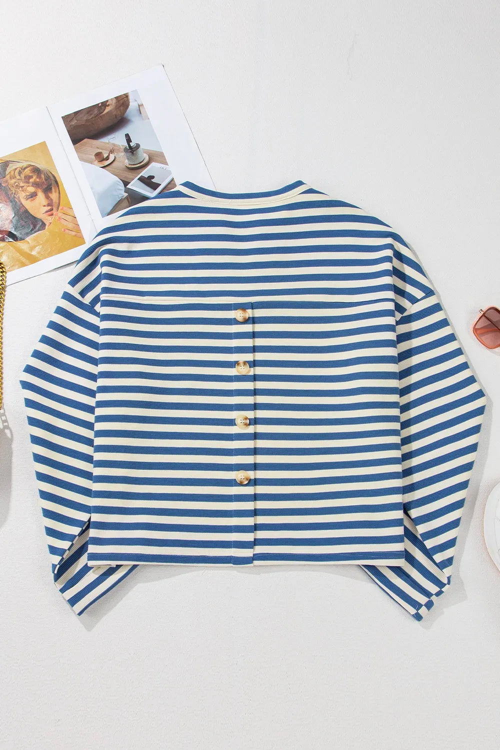 Blue and white striped long-sleeve top with vertical buttoned back placket