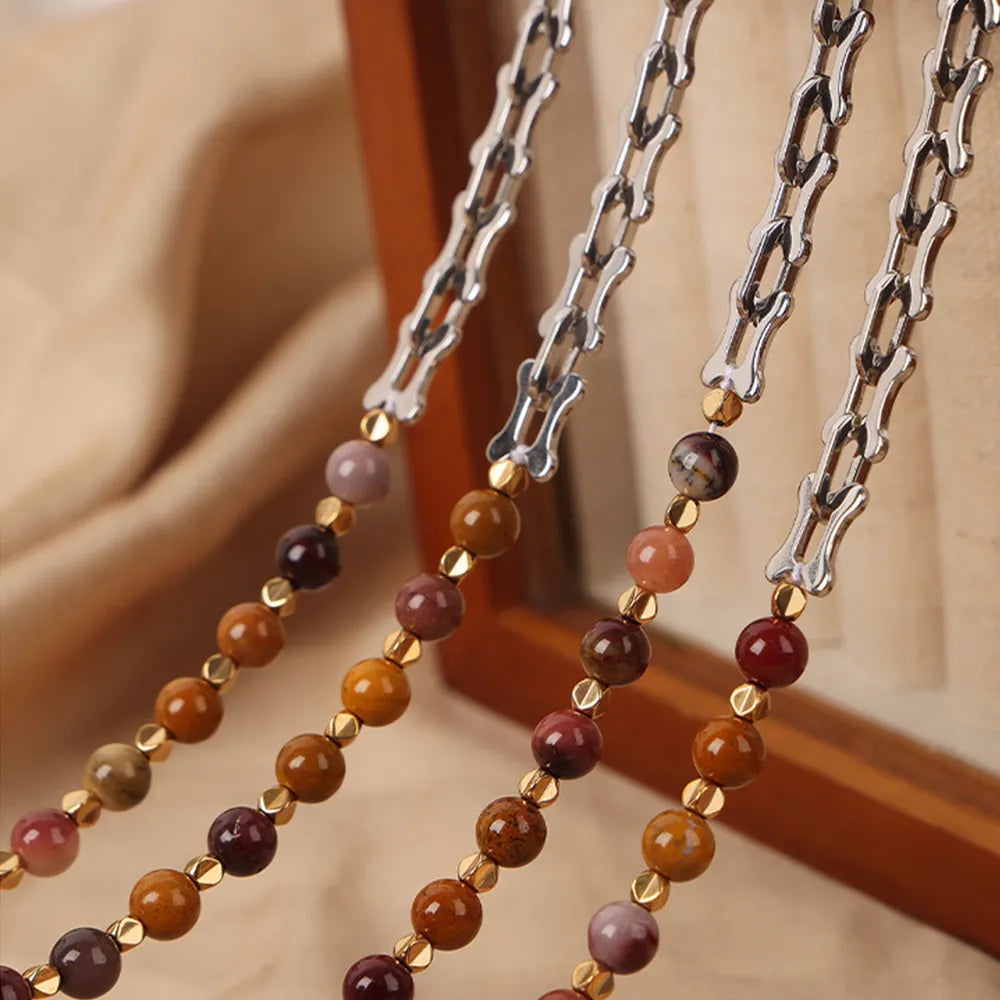 Beaded necklaces with silver-tone chains and multicolor round stone beads draped on blocks
