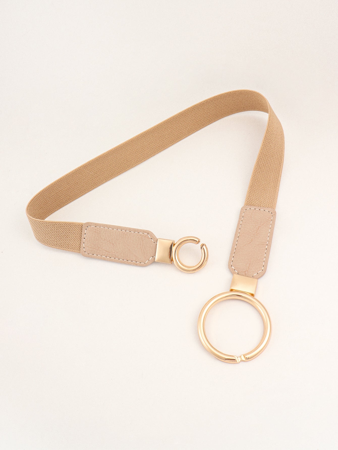 Beige elastic vegan leather belt with gold-toned double-ring buckle and adjustable tabs