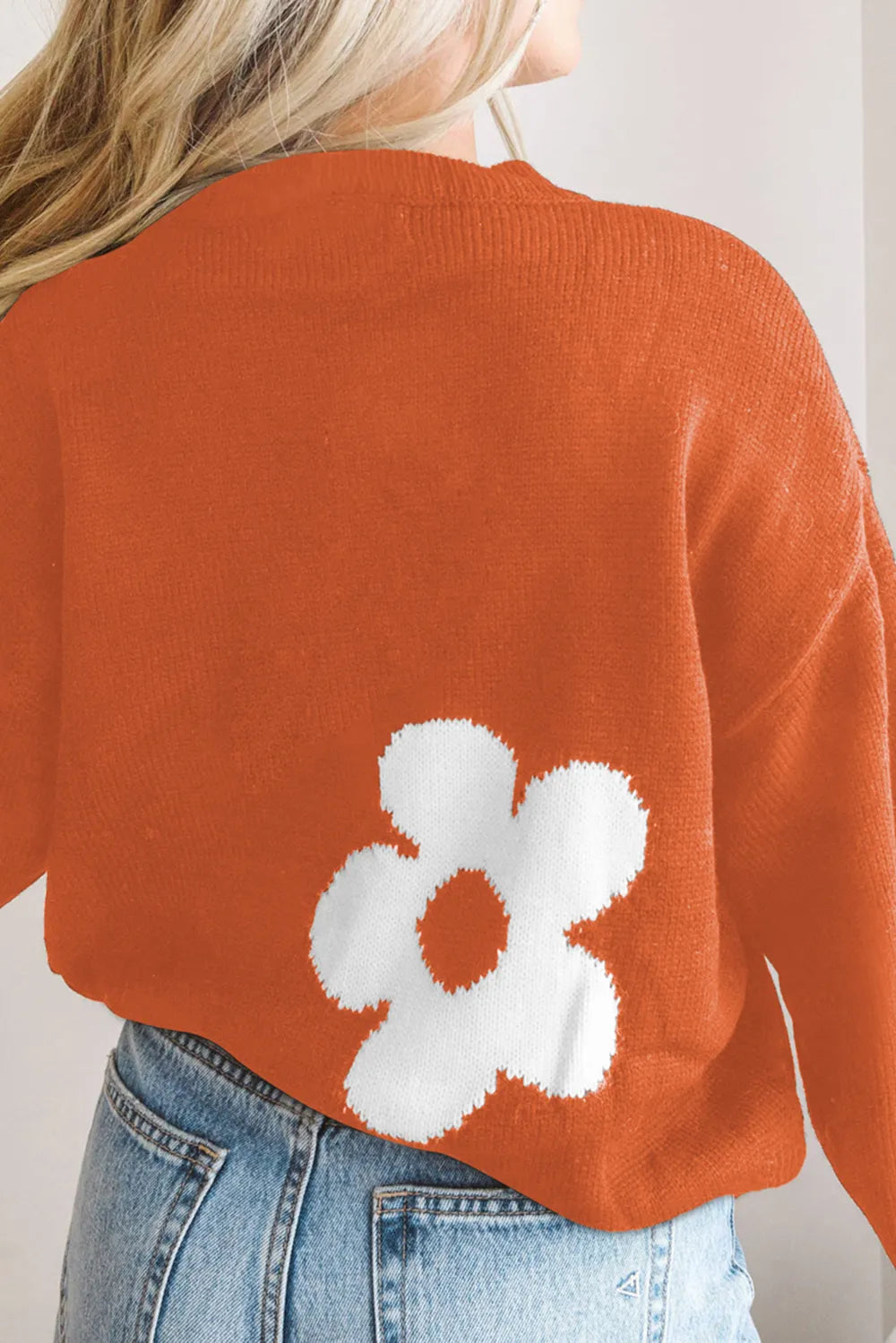 Orange long-sleeve sweater with round neck and white flower motif on back