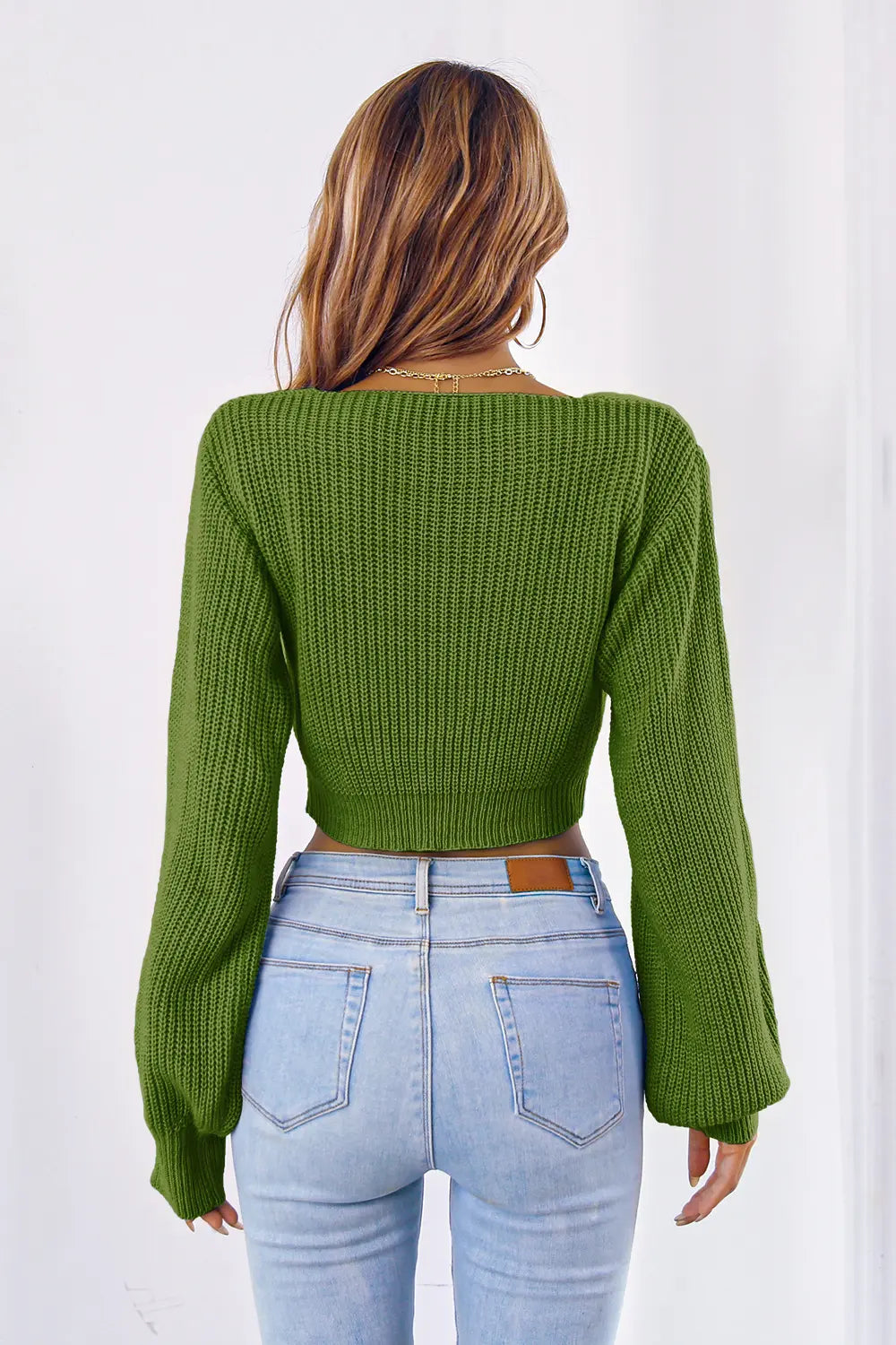 Green knit cropped sweater with long sleeves; V-neck back view with ribbed texture.