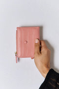 Pink textured vegan leather mini wallet with gold zipper, wrist strap, and snap button.