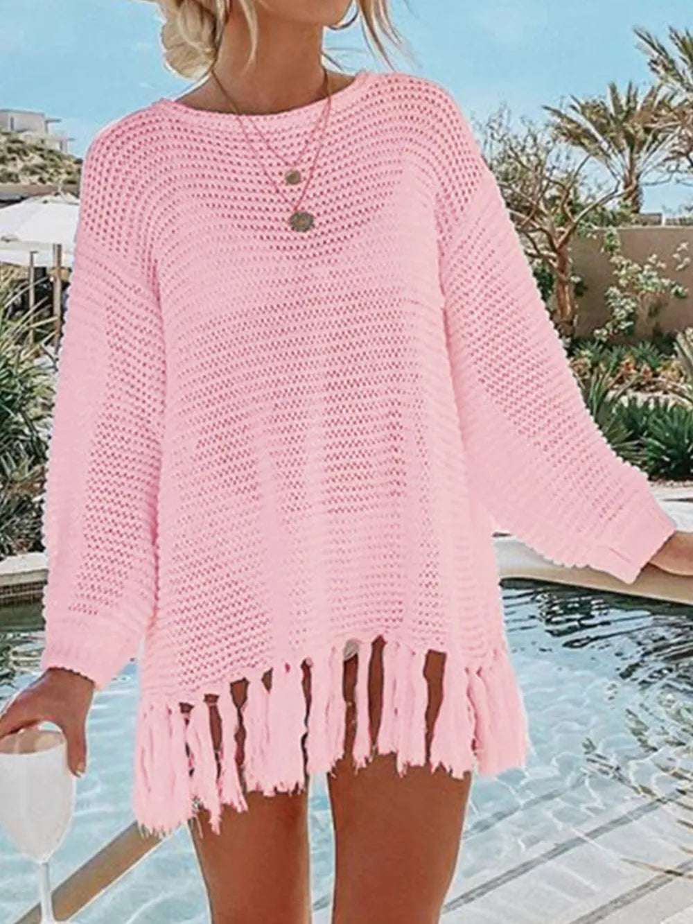 Blush pink long-sleeve openwork knit cover up with tassel fringe hem.