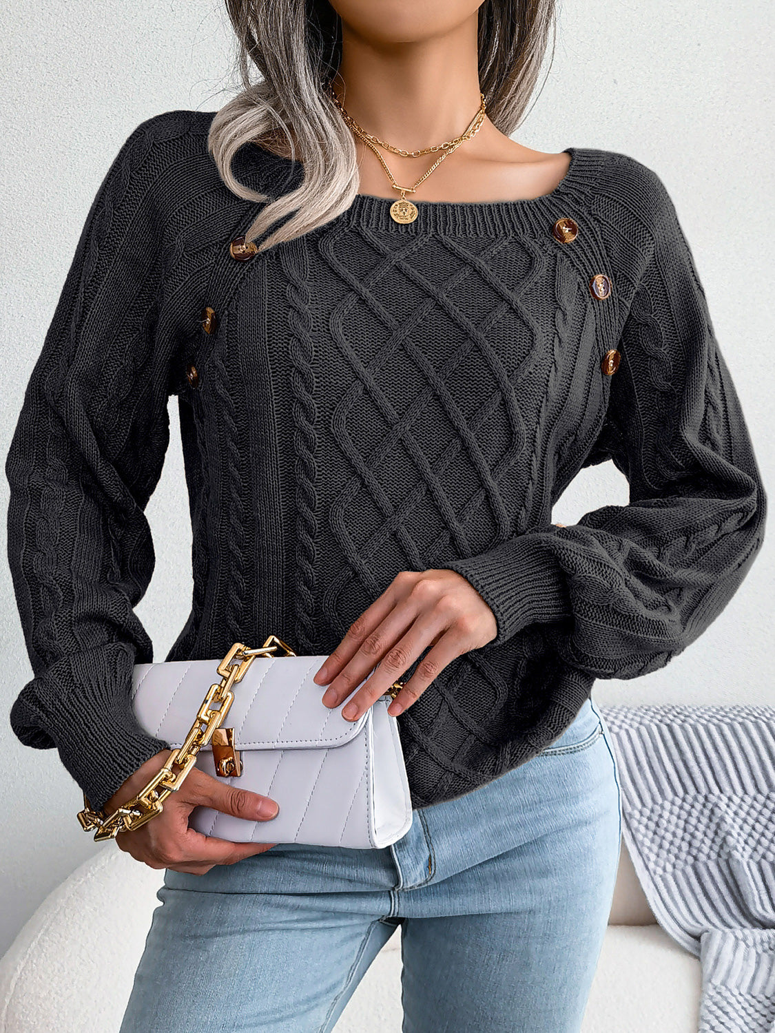 Black cable-knit sweater with diamond lattice knit and decorative button accents