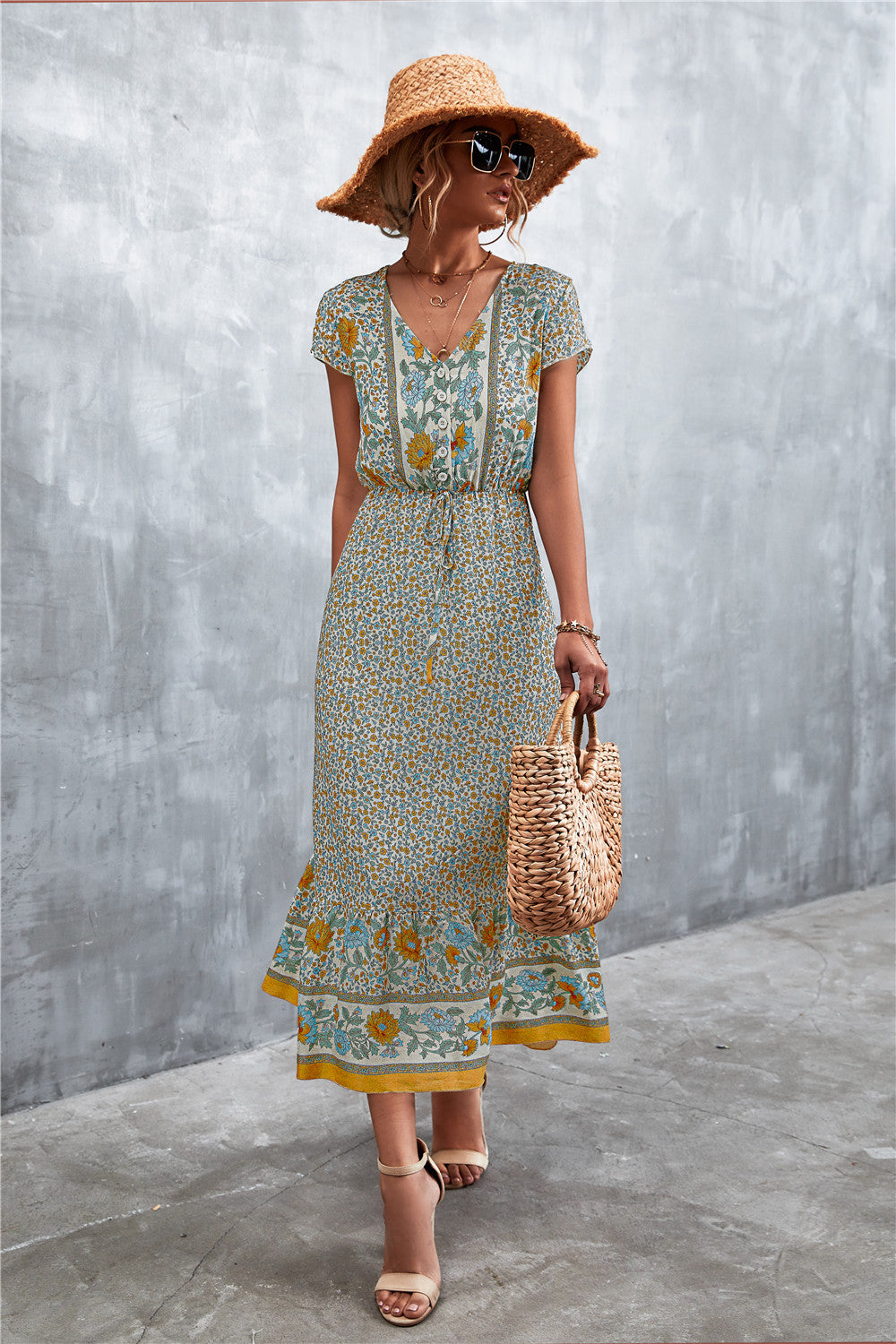 V-neck printed maxi dress with short sleeves, beige base, teal floral band hem.