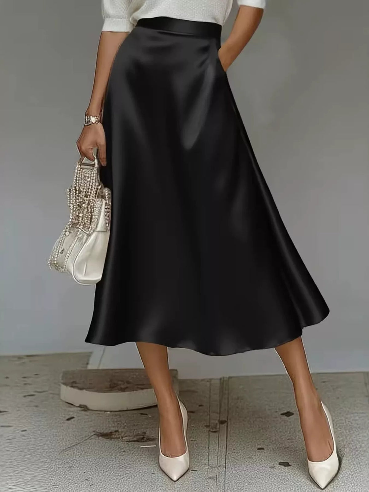 High-waist satin midi skirt in black, flared A-line shape with glossy surface.