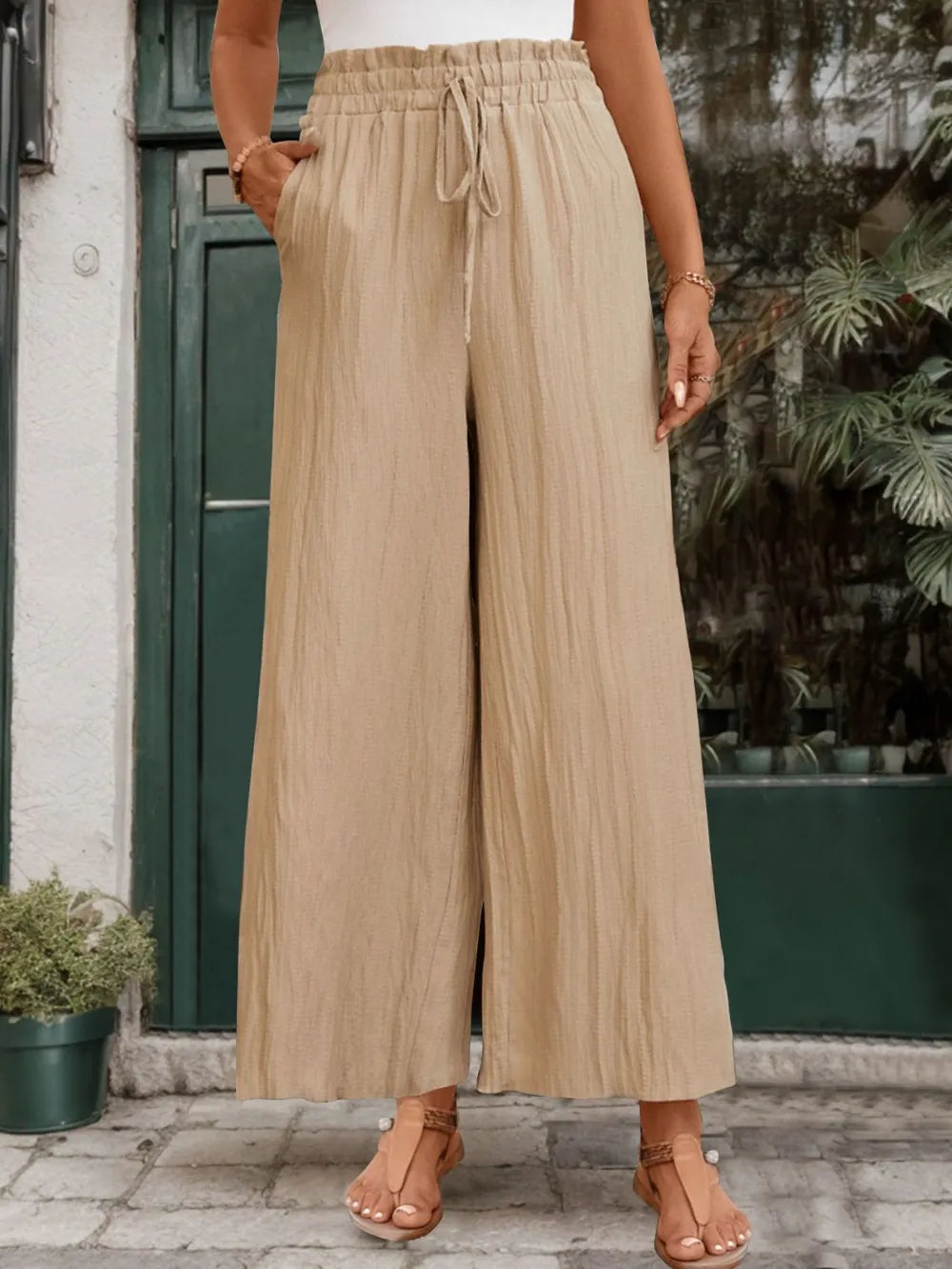 Tan wide-leg pants with elastic waist and drawstring, full length.