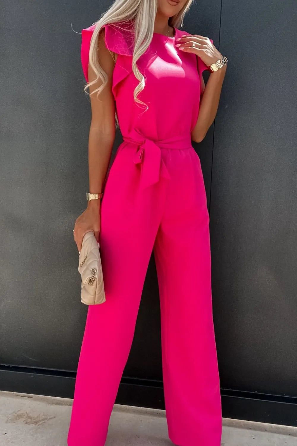Hot pink cap sleeve jumpsuit with round neckline, tied waist, and wide leg pants