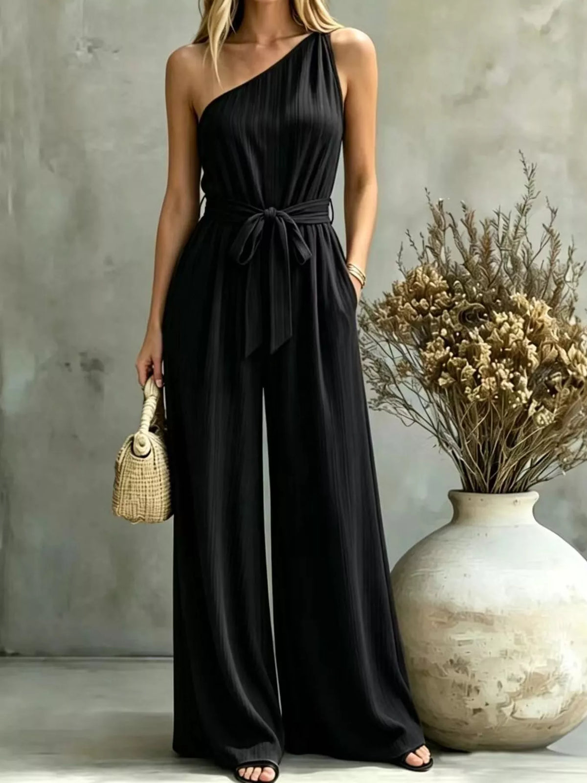 One-shoulder pleated wide-leg jumpsuit in black with self-tie waist and wide pants