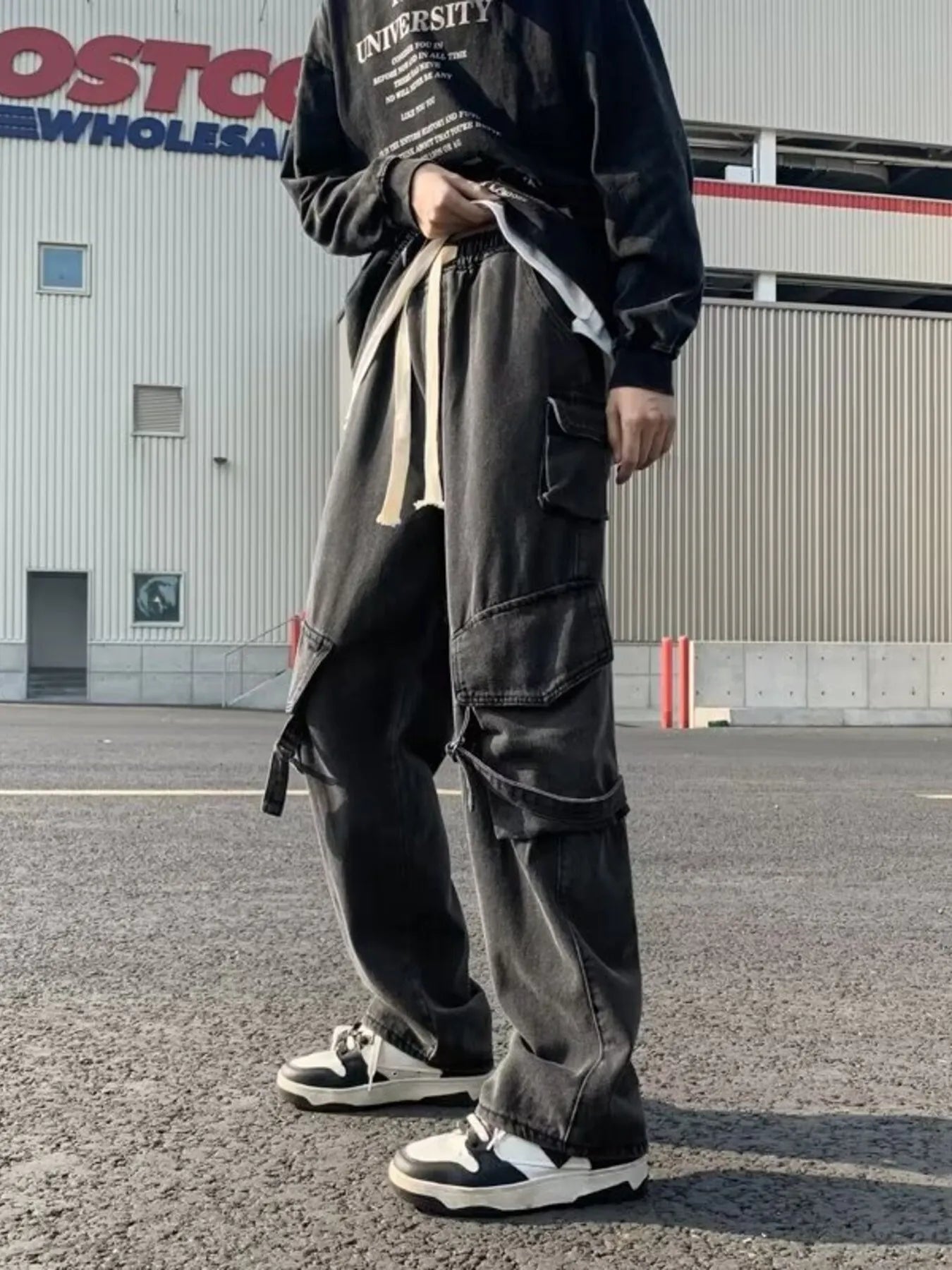 Black wide-leg cargo jeans with drawstring waist, layered cargo pockets and side tie