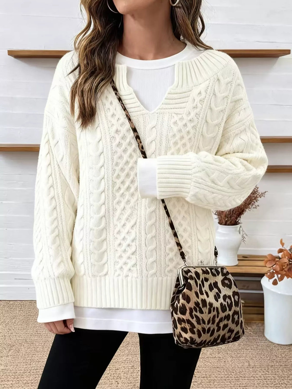 Off-white cable knit sweater with dropped shoulders, V-neck, and ribbed cuffs