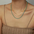 Double-layer turquoise bead necklace with gold curved chain, close-up on neckline