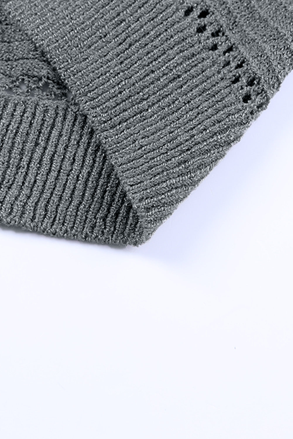 Gray knit cardigan sleeve detail with openwork stitching and ribbed cuff