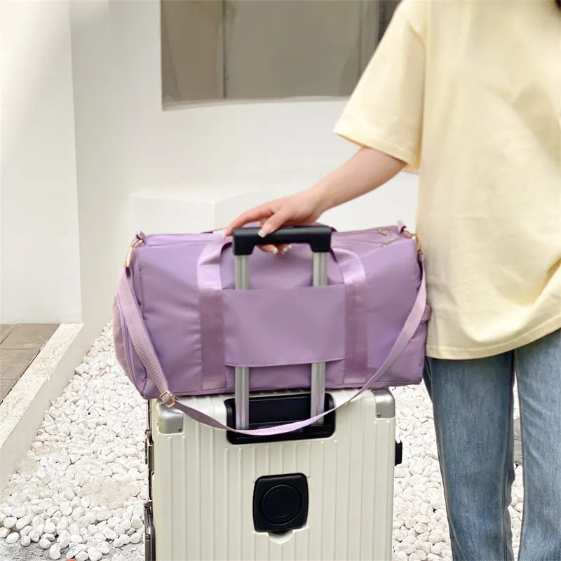Large duffel bag with front pocket, lavender color, secured on a rolling suitcase