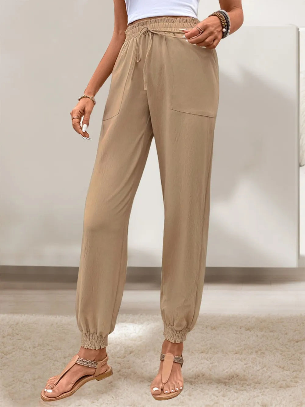Tan elastic-waist drawstring pants with side pockets and ankle cuffs
