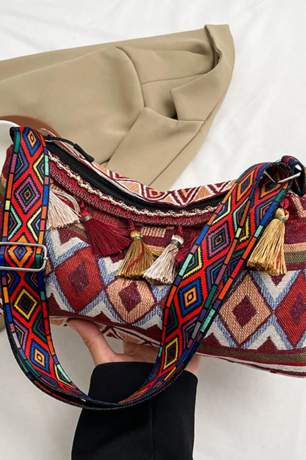 Geometric shoulder bag with tassel details, adjustable strap, and zippered top in multicolor