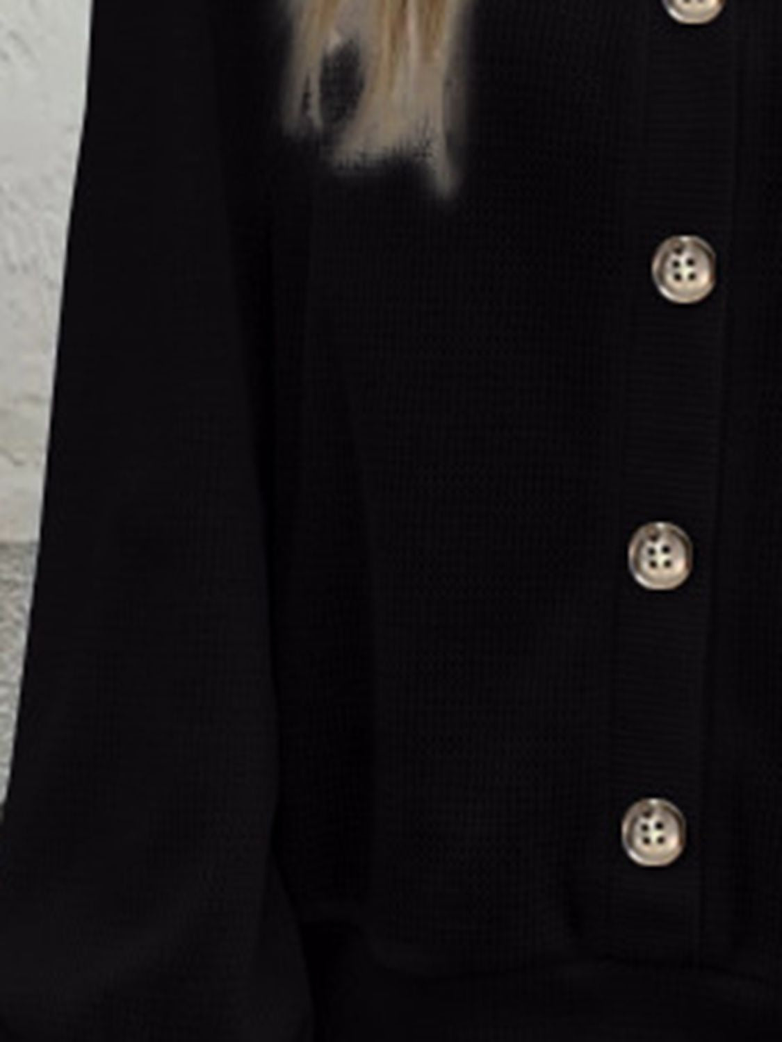 Black blouse close-up: V-neck button placket with small gold-tone buttons