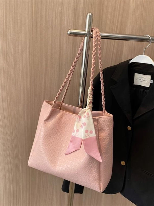 Blush pink braided handle tote bag with bow scarf accessory, hanging from hook