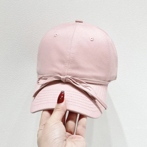 Blush pink baseball cap with bow-tie detail and curved brim