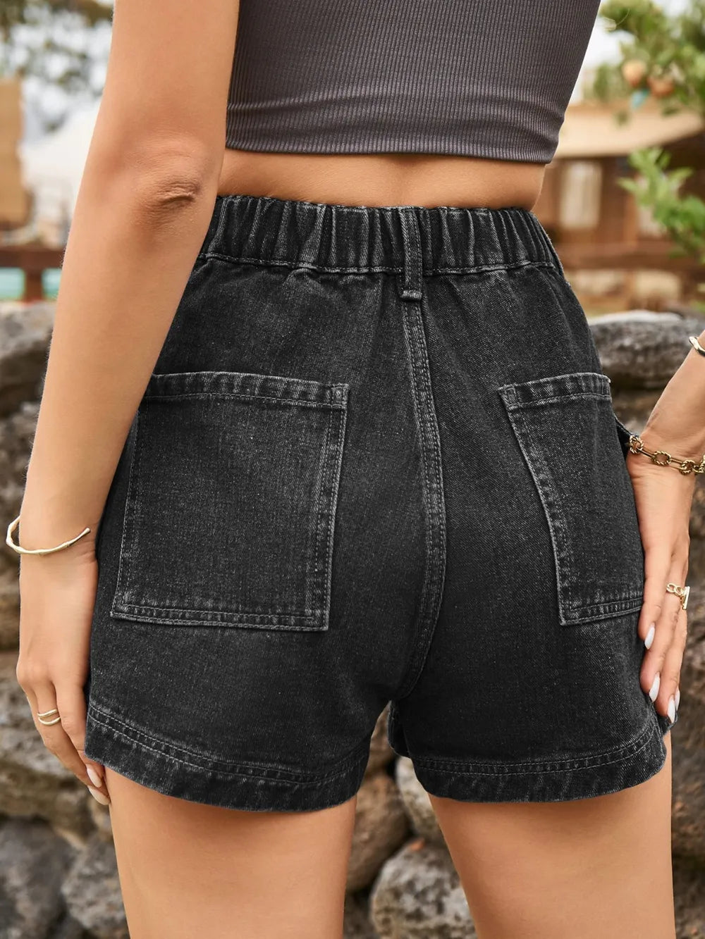 Dark denim high-waist shorts with elastic waistband, front button, and two patch pockets