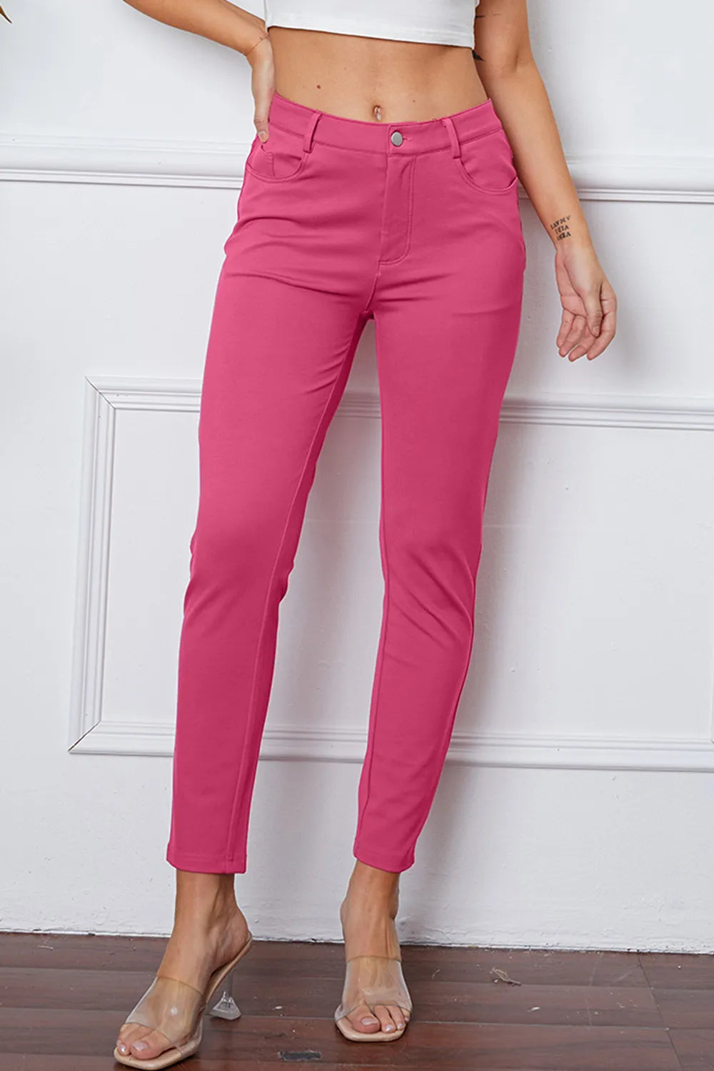 Stretchy pink pants with button waistband and slim ankle-length leg, front view