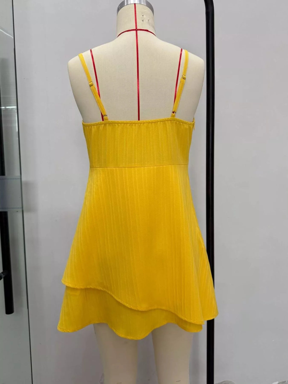 Yellow spaghetti strap mini dress on mannequin, open back and tiered hem