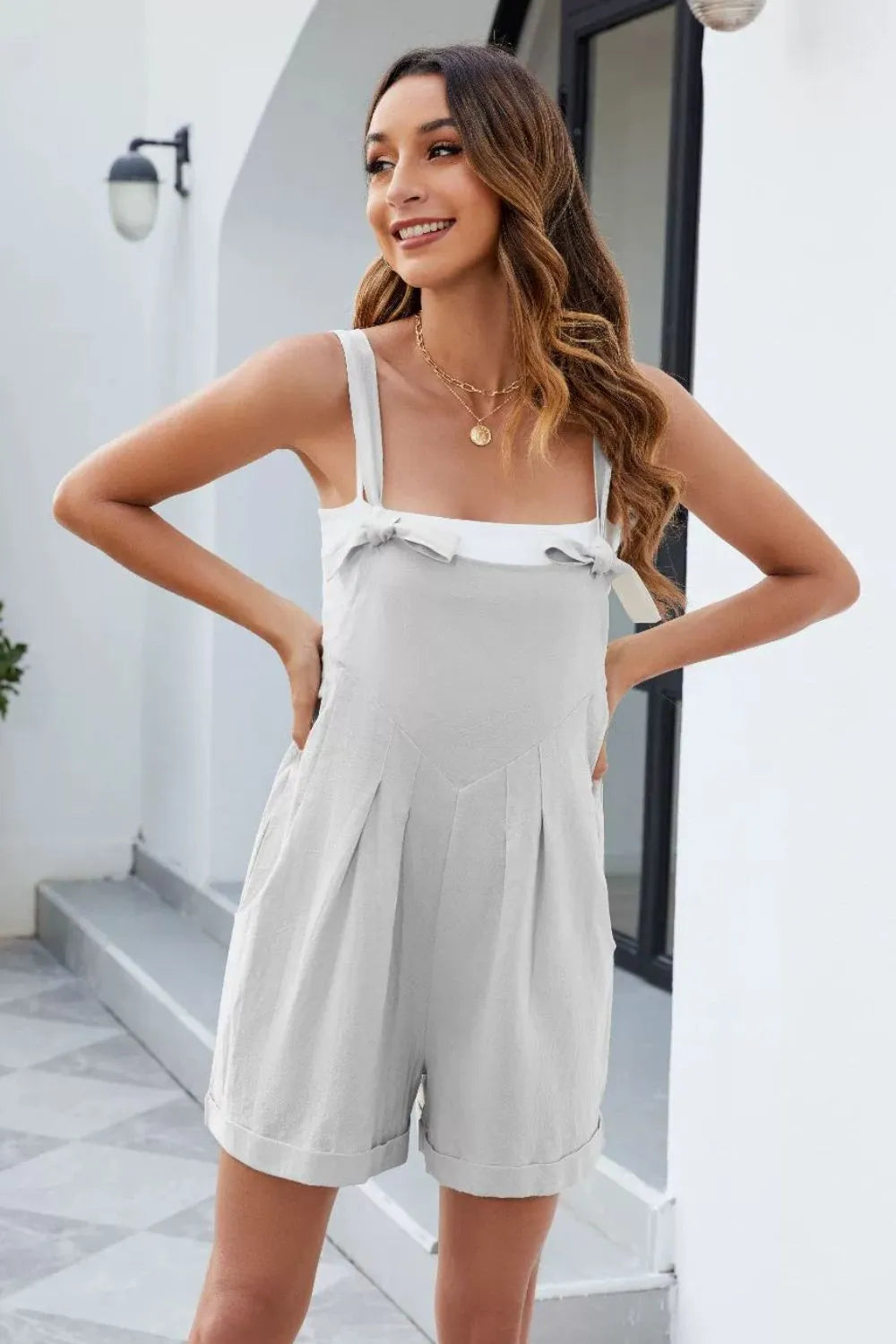 White knotted-strap romper with pockets, adjustable tie straps, and tiered front