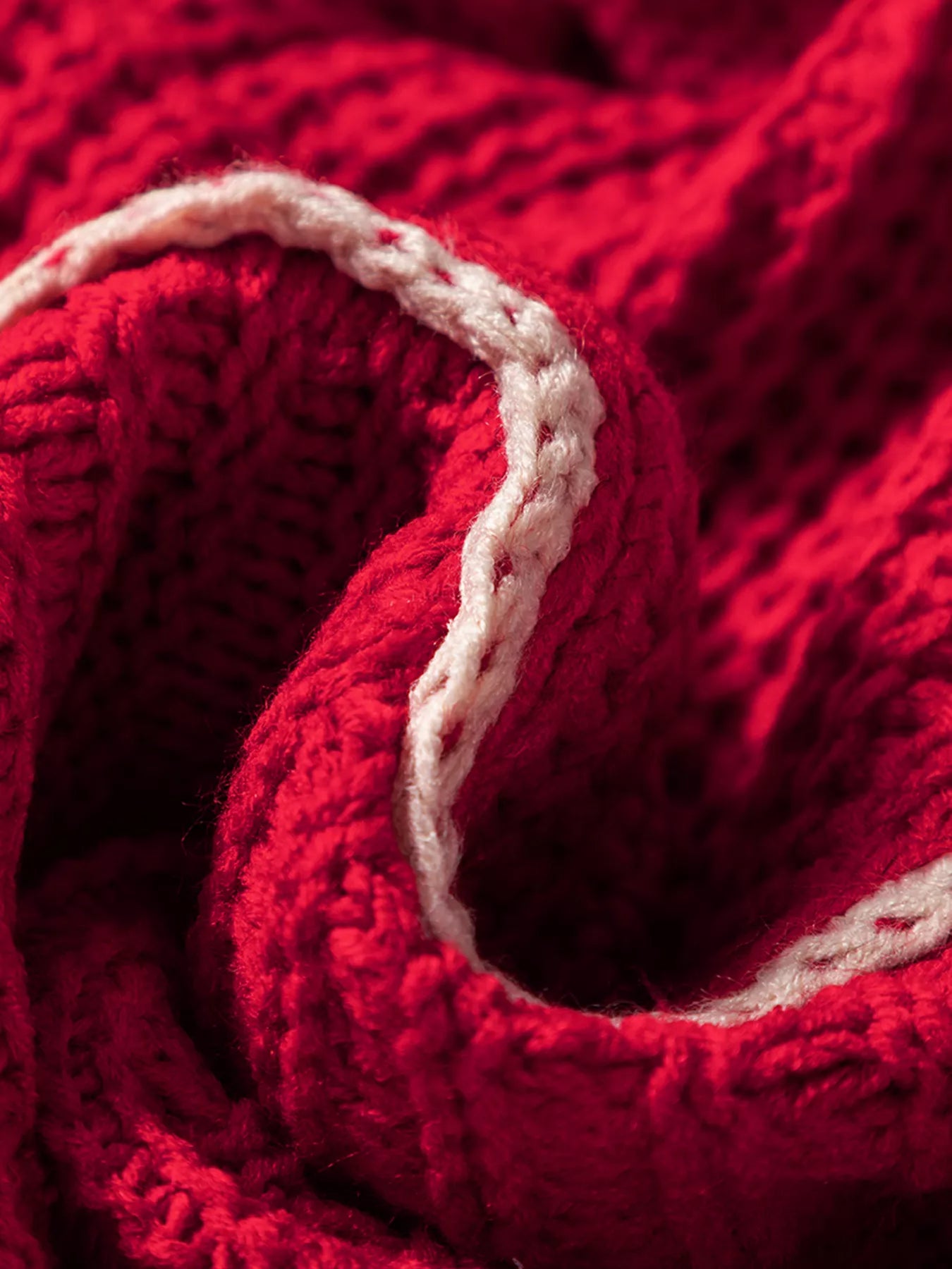 Deep red textured knit fabric close-up with off-white contrast trim edging