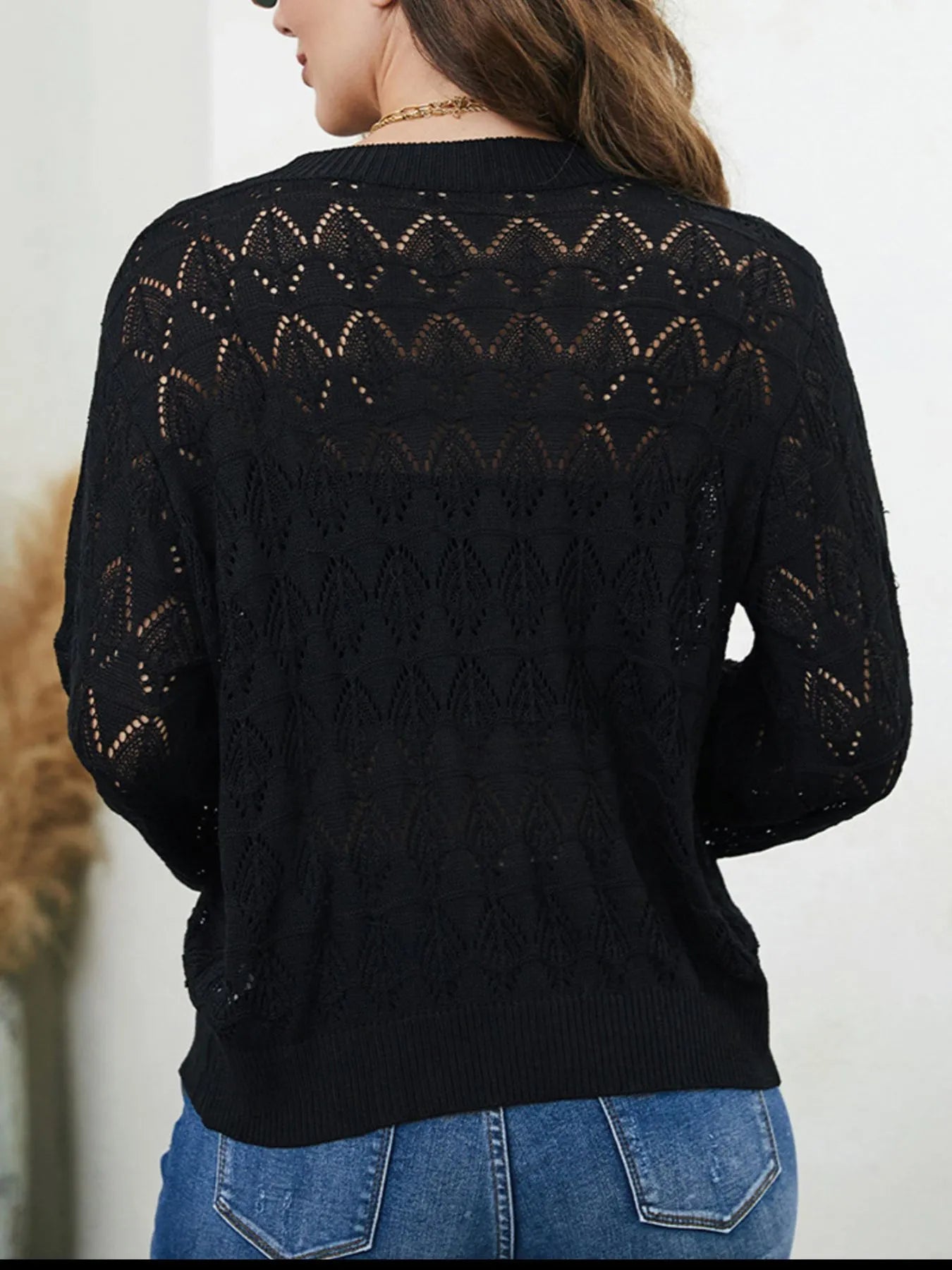 Black openwork cardigan sweater with button front and long sleeves, back view