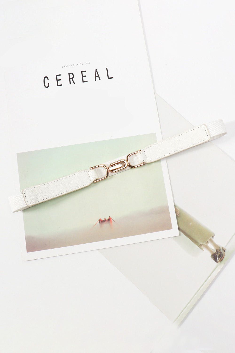 White elastic belt with silver-tone buckle and stitched strap edges