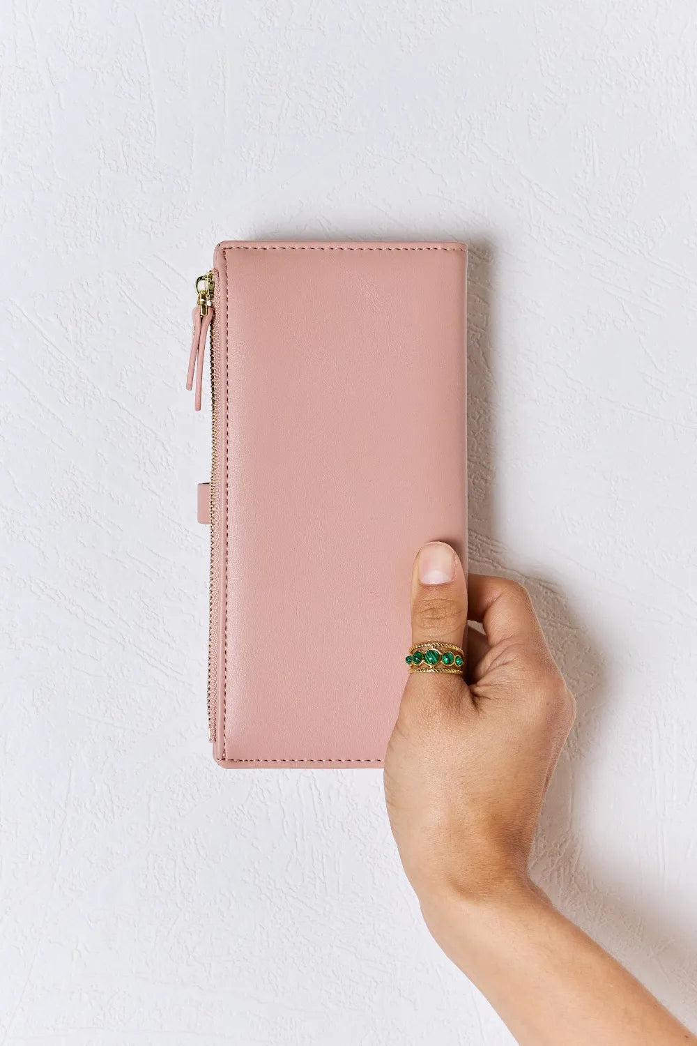 Pink textured PU leather wallet with gold-tone zipper and slim profile, hand-held.