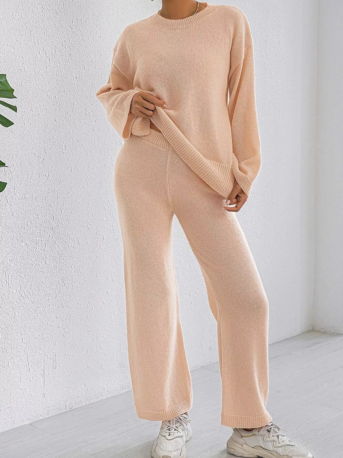 Apricot knit sweater and pants set with dropped shoulders and ribbed hems, relaxed wide legs.